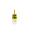 A gold pendant featuring a square-cut green peridot gemstone and a small round diamond accent, shown on a clean white background with a soft reflection below.