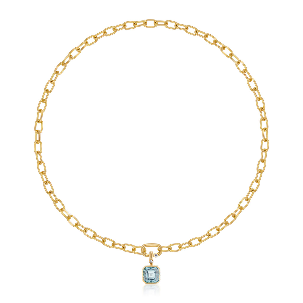 A gold chain necklace with a gold pendant featuring a square-cut light blue aquamarine gemstone and a small round diamond accent, shown on a clean white background with a soft reflection below.