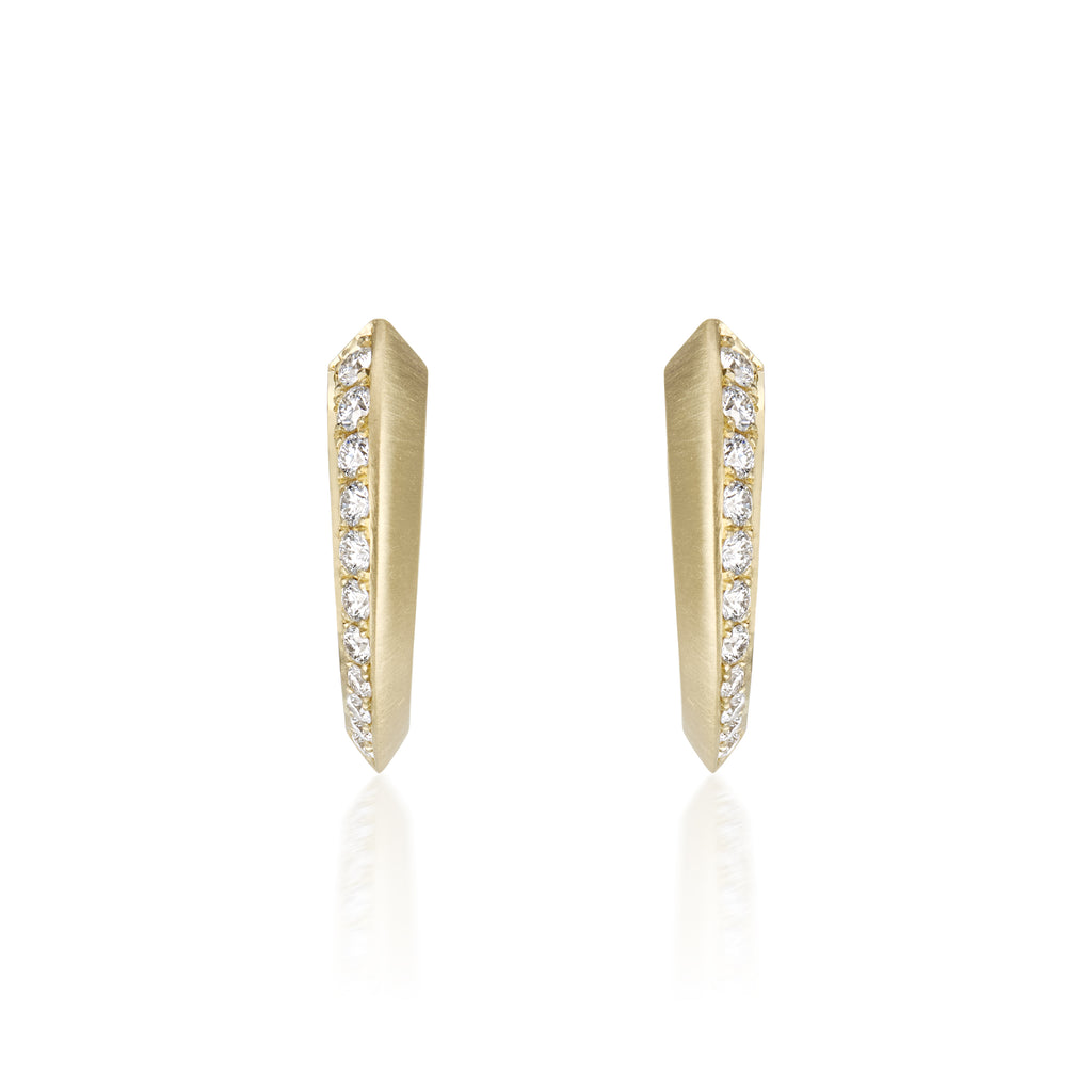 A pair of gold huggie hoop earrings with a row of diamonds pavé-set stones along the front edge, shown on a clean white background with a soft reflection below.