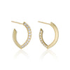 A pair of gold huggie hoop earrings with a row of diamonds pavé-set stones along the front edge, shown on a clean white background with a soft reflection below.